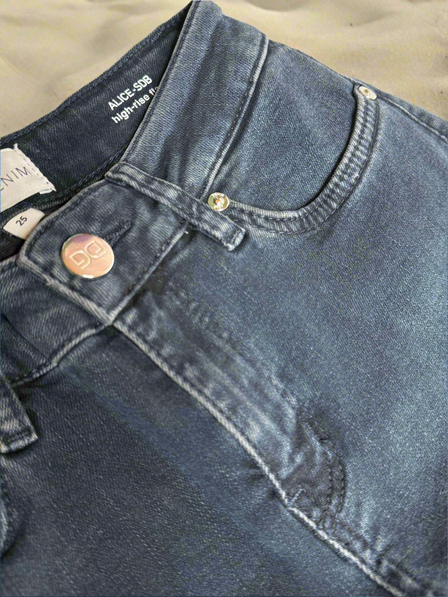 Close-up of blue denim jeans with a button and zipper detail on a white background