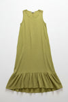 Green dress with ruffled hem on a hanger against a white wall.
