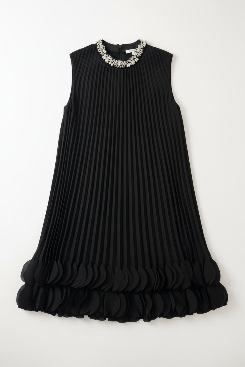 Black pleated dress with embellished neckline on a hanger against a white wall
