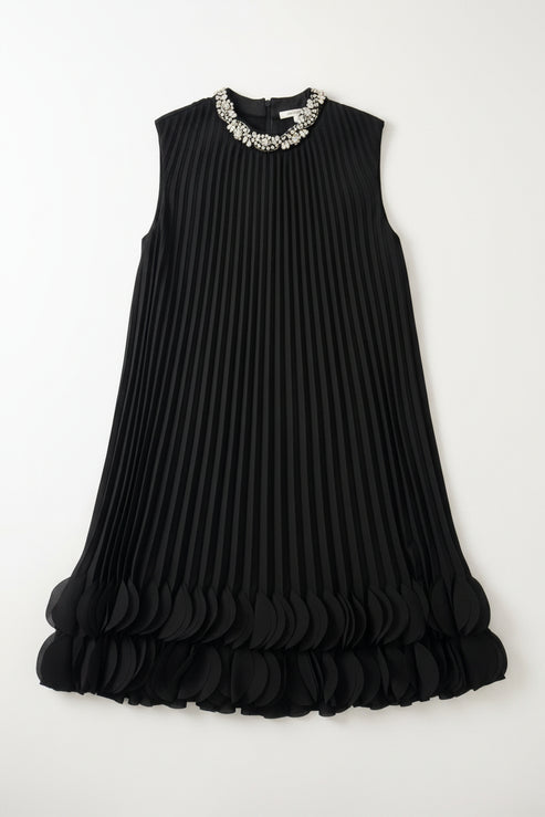 Black pleated dress with embellished neckline on a hanger against a white wall