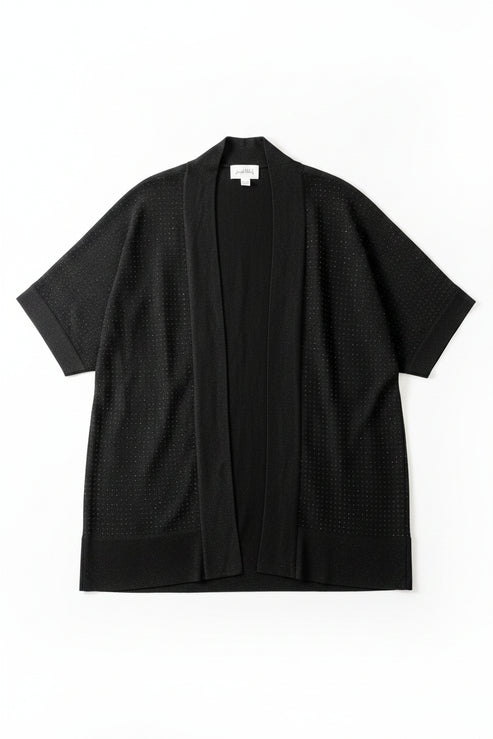 A black open-front cardigan sweater with three-quarter sleeves hanging on a black hanger against a textured off-white wall. The cardigan has a subtle dotted texture and features a hangtag and a white size label.