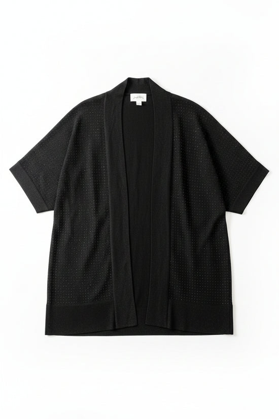 A black open-front cardigan sweater with three-quarter sleeves hanging on a black hanger against a textured off-white wall. The cardigan has a subtle dotted texture and features a hangtag and a white size label.