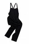 Black overalls with a brand label on a light beige background