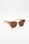 Brown sunglasses on a wooden surface with a light gray wall background