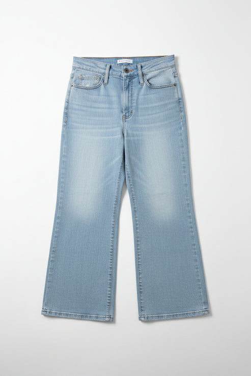 Blue jeans hanging on a rack against a beige wall.