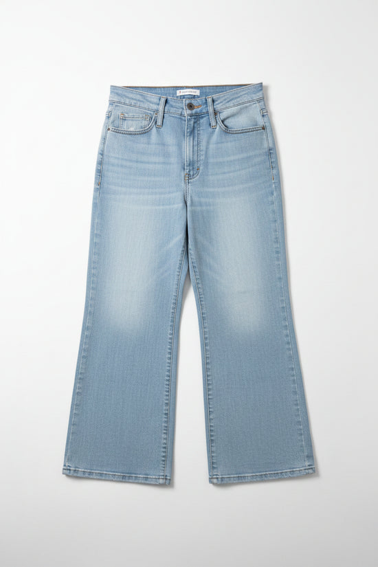 Blue jeans hanging on a rack against a beige wall.