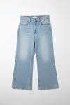 Blue jeans hanging on a rack against a beige wall.
