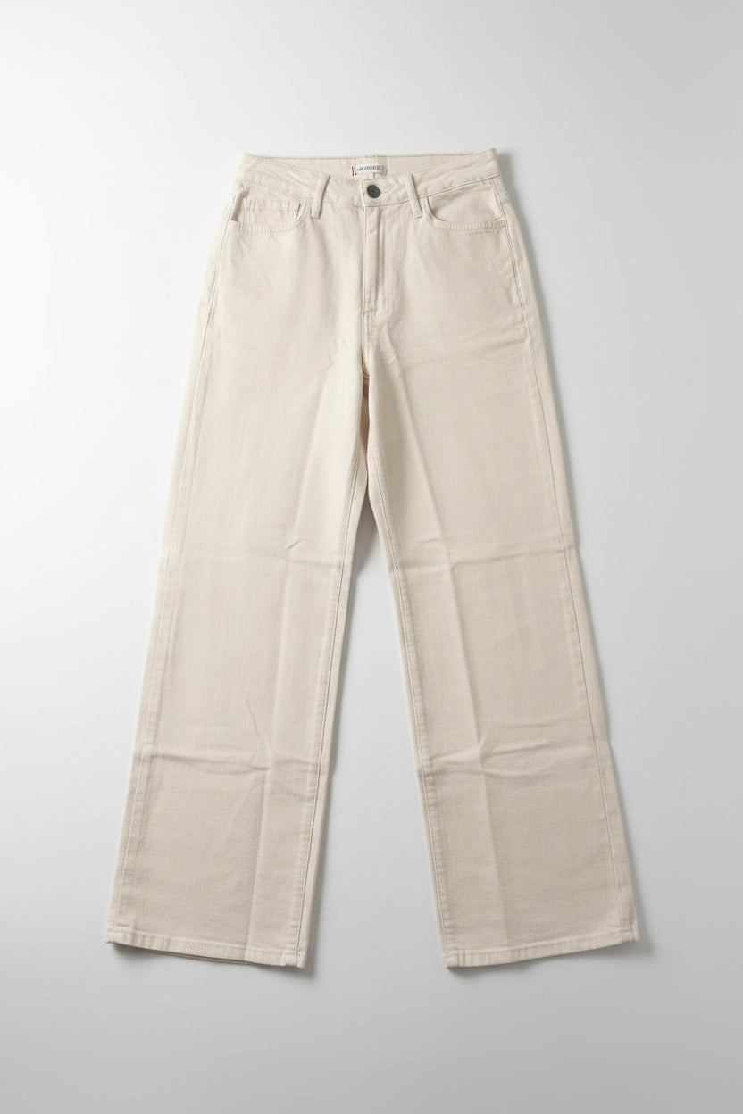 Beige pants hanging on a black hanger against a white wall.
