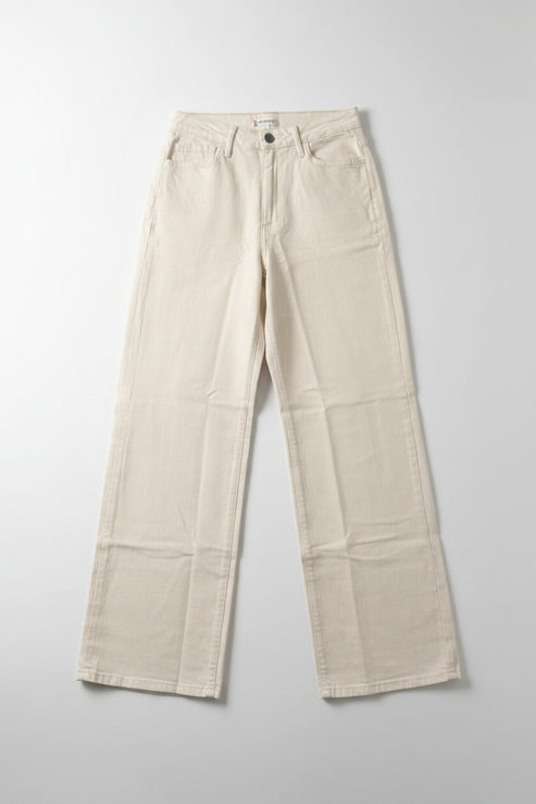 Beige pants hanging on a black hanger against a white wall.
