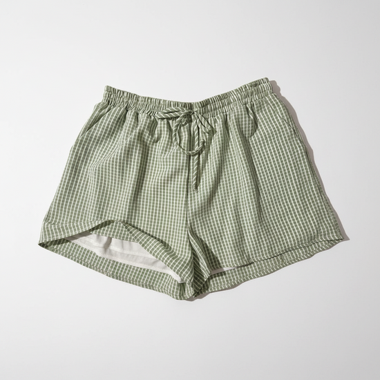 Green checkered shorts on a white surface with a blurred background