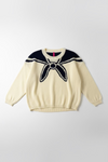 Sailor-style sweater with navy collar and trim on a hanger against a white wall.