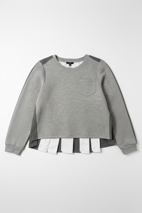 A heather gray long-sleeve top with dark gray shoulder panels and a chest pocket, hanging on a black hanger against a textured off-white wall. A white shirt is layered underneath at the hem.