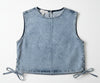 Denim vest on a hanger against a beige wall