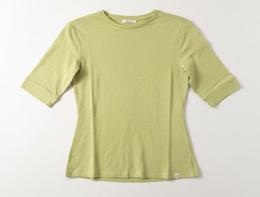 Green t-shirt on a hanger against a white wall