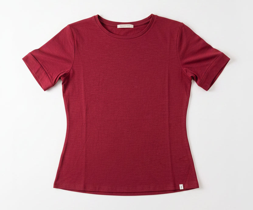 Maroon t-shirt on a hanger against a white wall