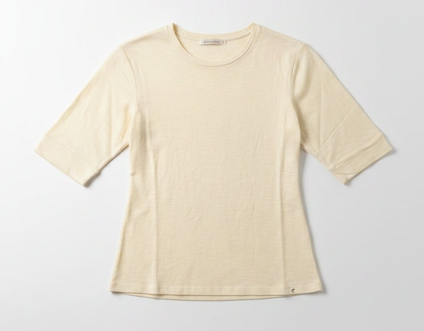 Beige t-shirt on a hanger against a plain wall