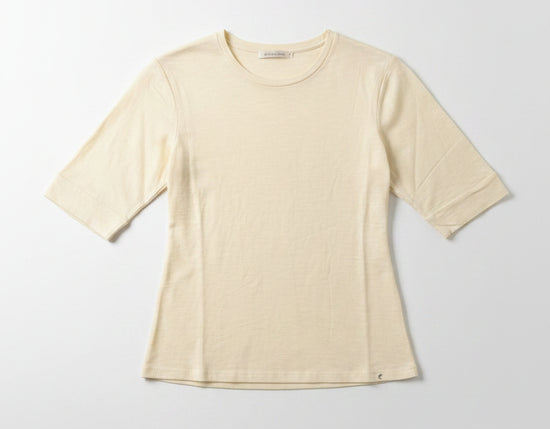 Beige t-shirt on a hanger against a plain wall
