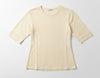 Beige t-shirt on a hanger against a plain wall