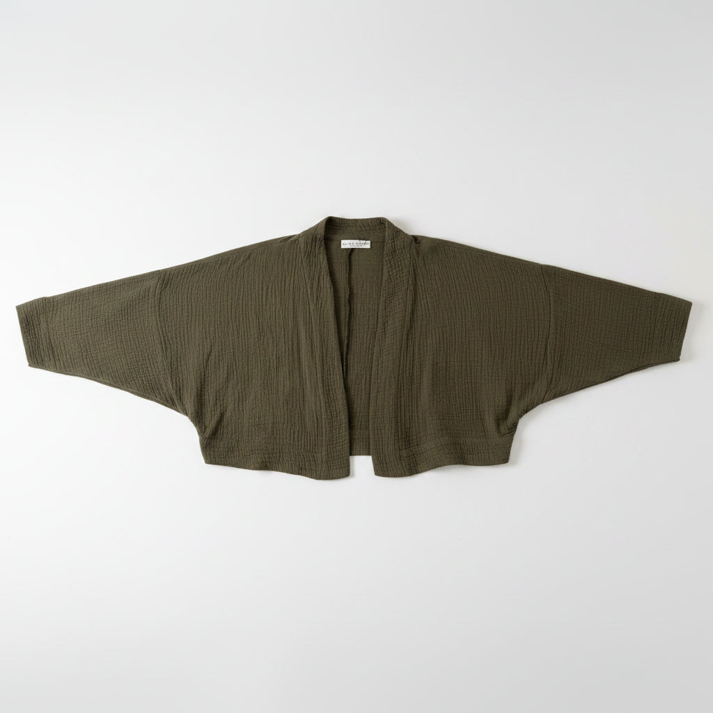 Green jacket on a hanger against a white wall with a visible tag.