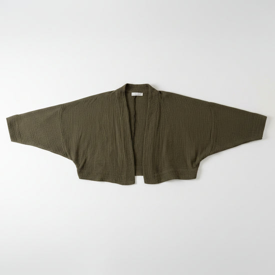 Green jacket on a hanger against a white wall with a visible tag.