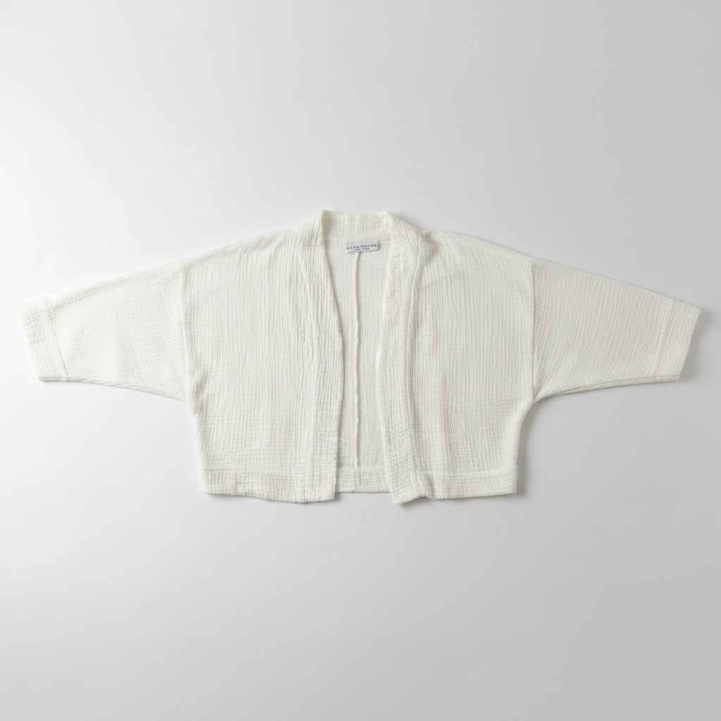 White textured jacket on a hanger against a plain white wall