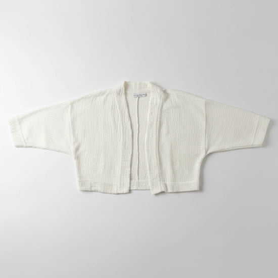 White textured jacket on a hanger against a plain white wall