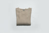 Folded beige sweater on a white surface