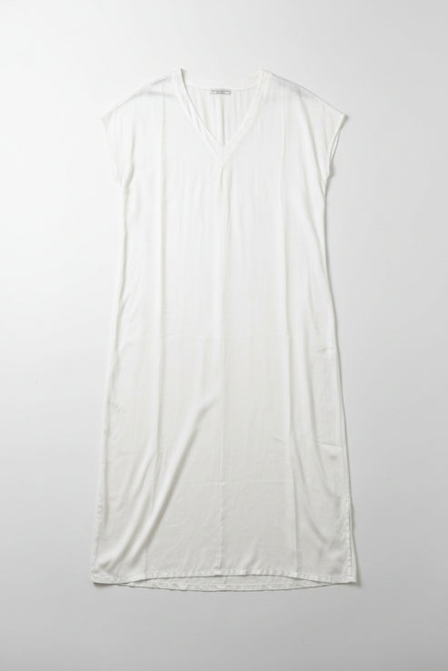 White sleeveless dress on a hanger against a white wall.