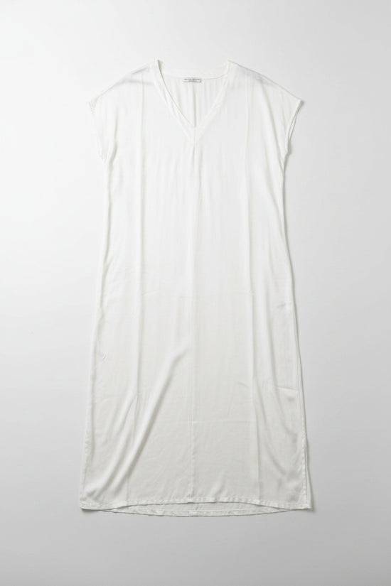 White sleeveless dress on a hanger against a white wall.