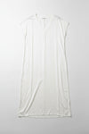 White sleeveless dress on a hanger against a white wall.