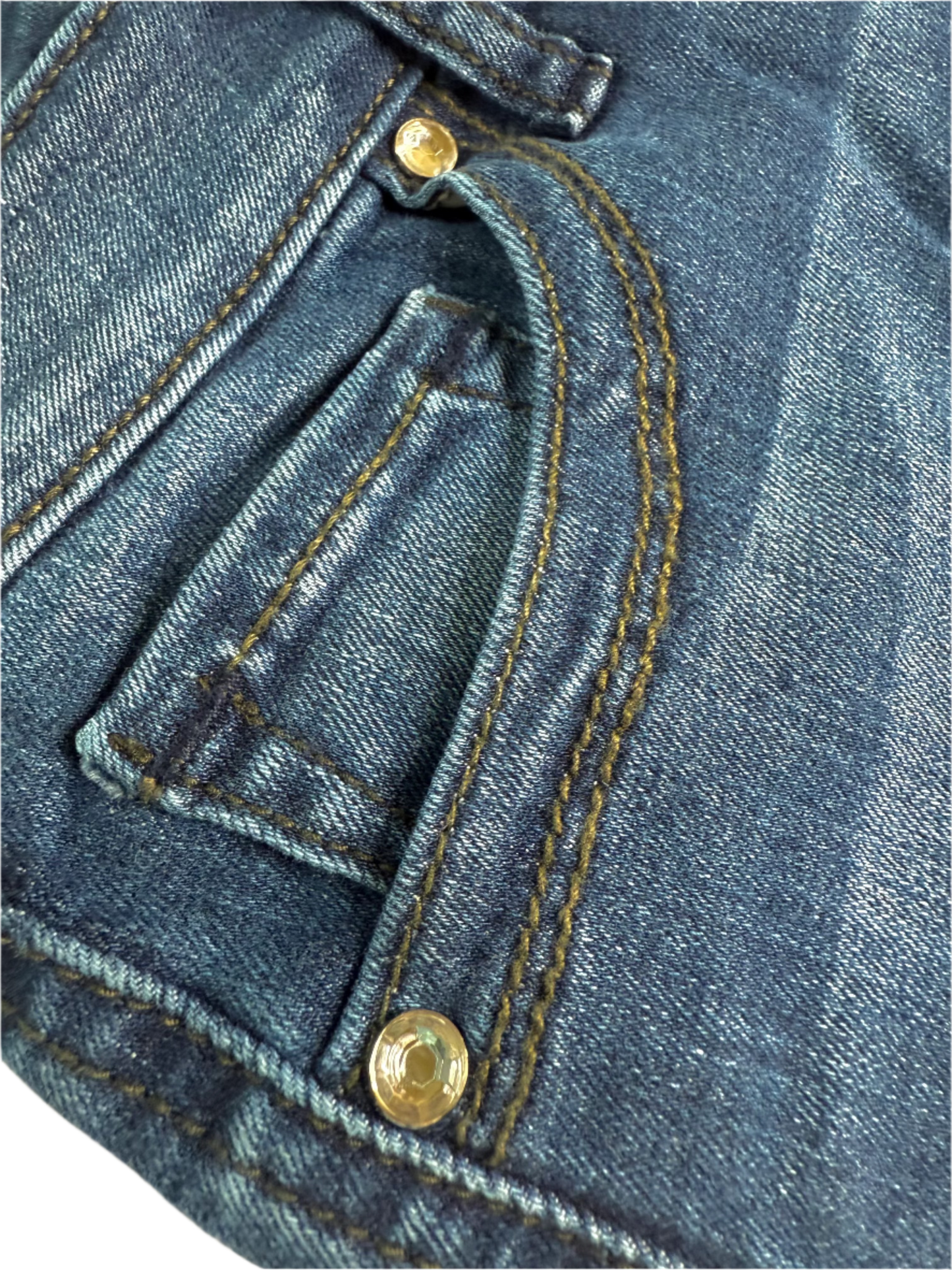 Close-up of blue denim fabric with stitching and buttons