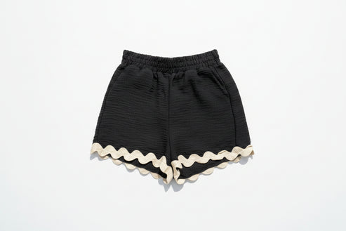 Black shorts with white trim on a grassy background with daisies