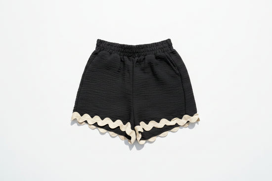 Black shorts with white trim on a grassy background with daisies