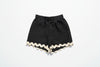 Black shorts with white trim on a grassy background with daisies