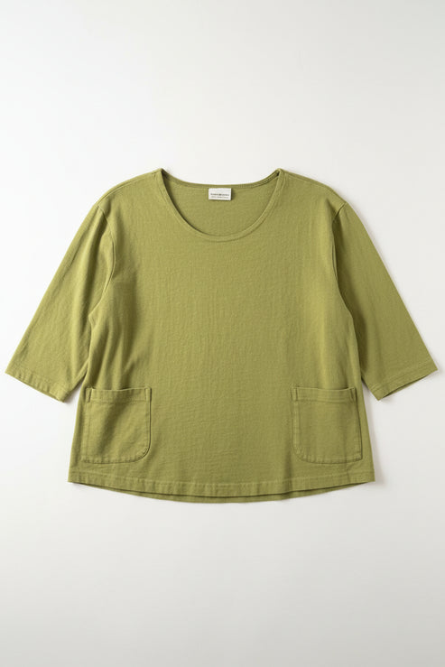 Green shirt laying flight on a white surface.