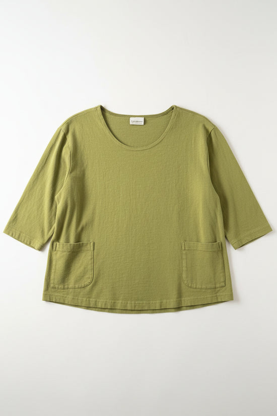 Green shirt laying flight on a white surface.