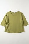 Green shirt laying flight on a white surface.